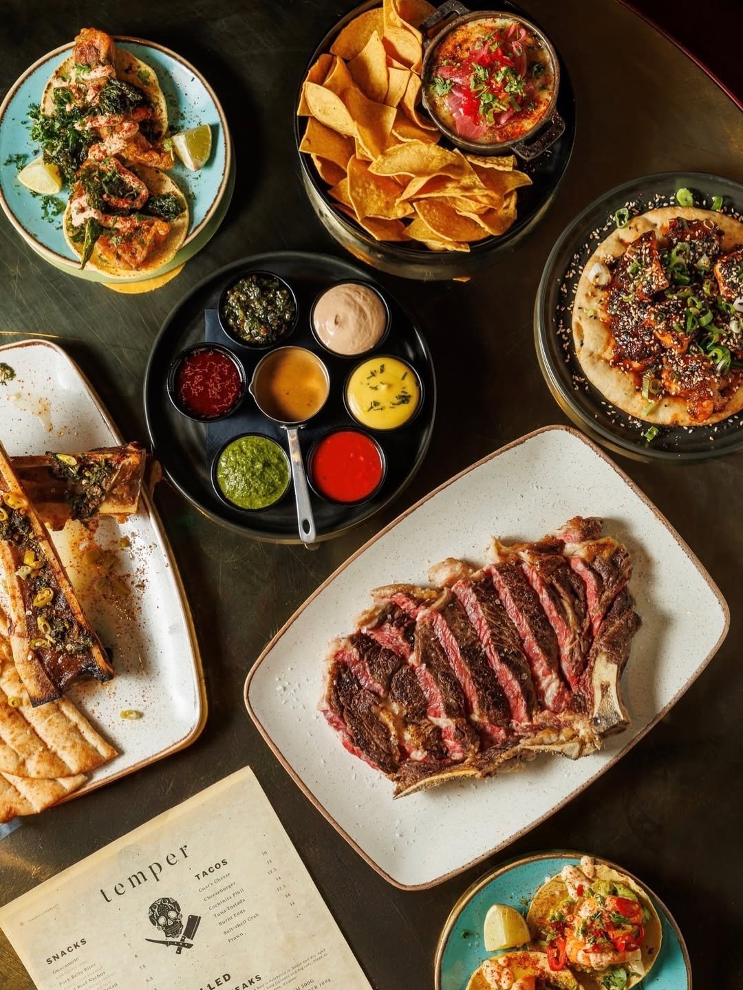 A table of tacos, sauces and steak at temper
